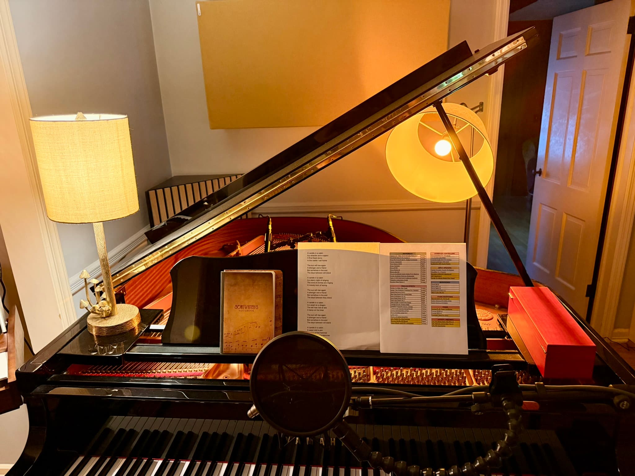 Music stand on the GC1 with a lyric sheet and a songwriter's notebook, mics in place over the strings